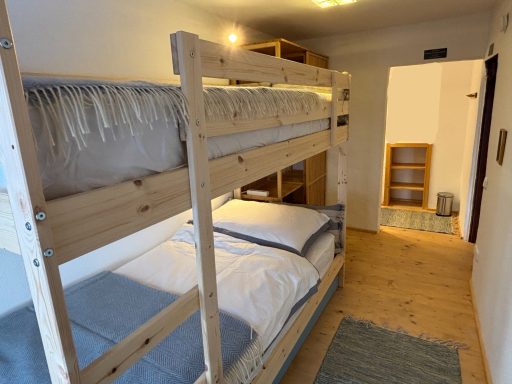 Gemütliche Schlafrakete mit Etagenbetten und Holzregalen in einem hellen Raum.